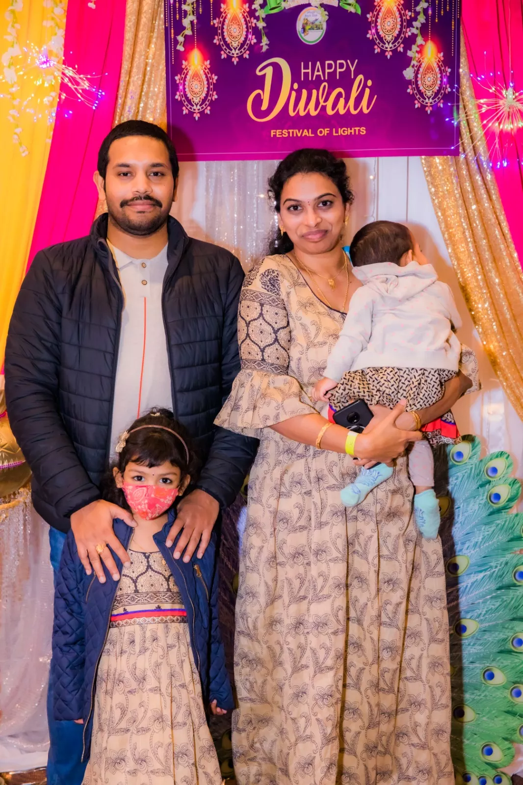Saisudha holding her younger daughter, standing next to her are her husband and the second daughter.