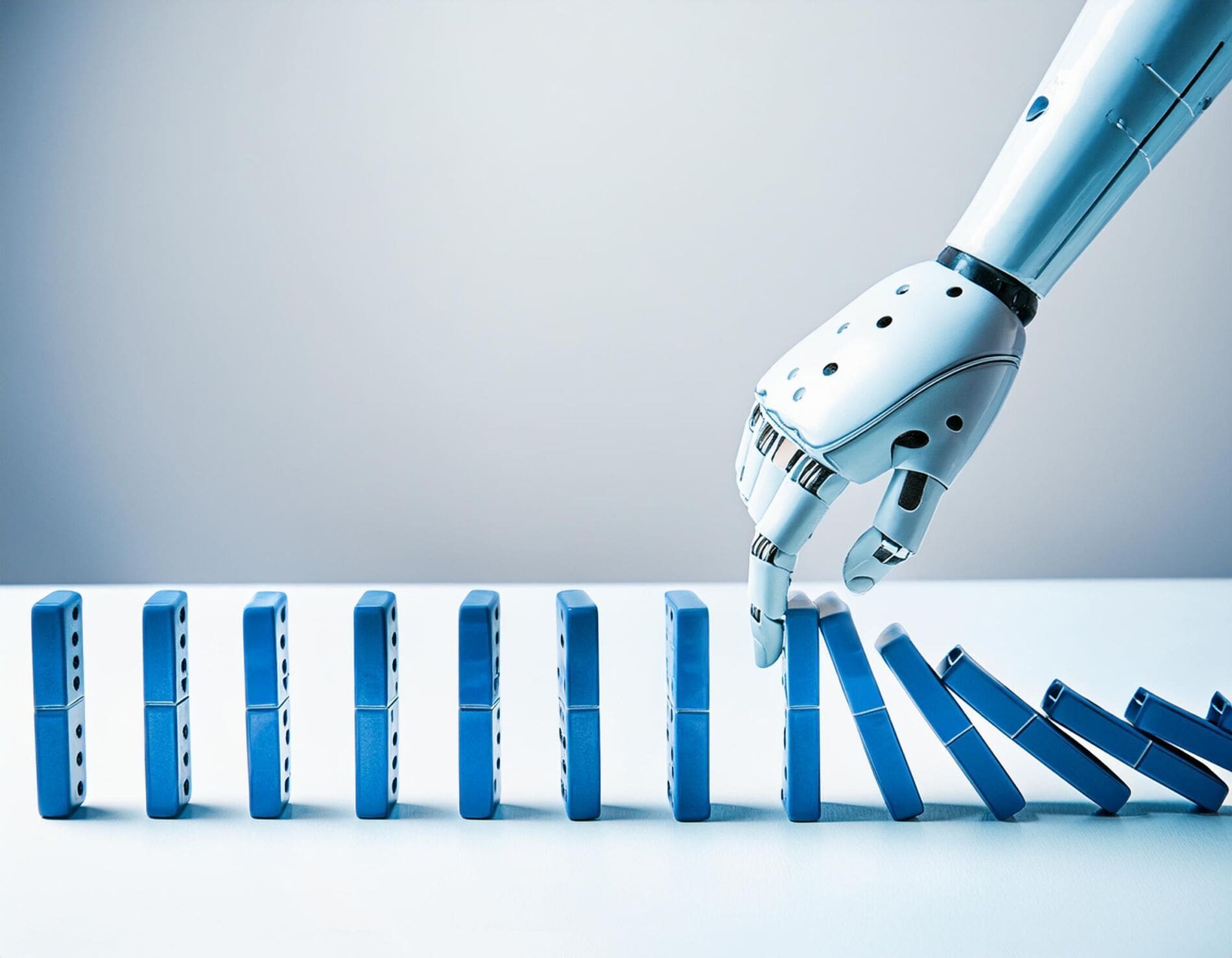 Shows a robot hand pushing blue dominos resulting in the domino effect. 