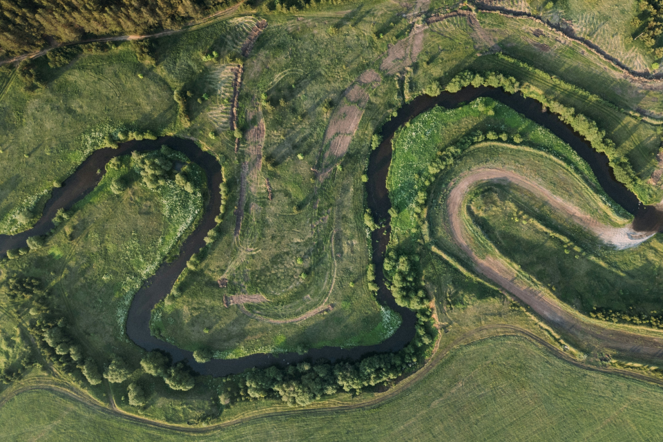 Aerial view of a winding creek flowing through a green landscape